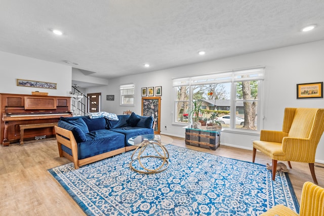 living area with recessed lighting, a textured ceiling, stairs, and light wood-style floors