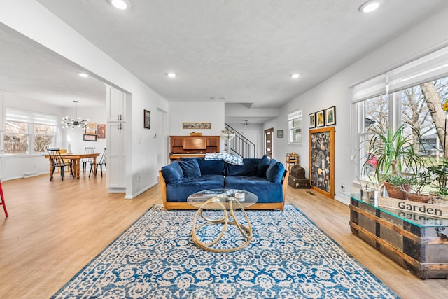 living area with an inviting chandelier, light wood-style flooring, recessed lighting, stairs, and a textured ceiling