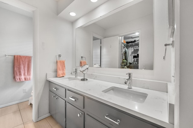 full bath featuring a sink, baseboards, a spacious closet, and double vanity