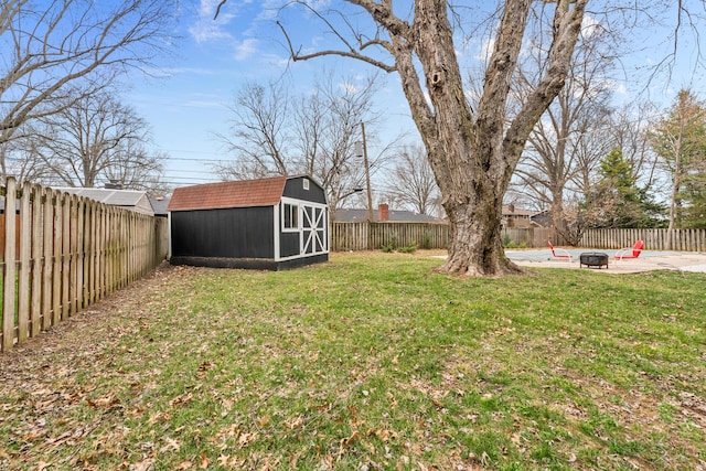 view of yard with an outdoor structure, a fenced backyard, a shed, and an outdoor fire pit