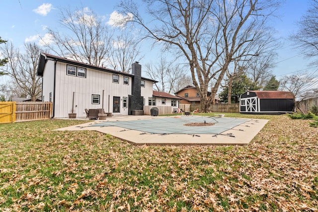 back of property with a patio, a fenced backyard, a storage shed, an outdoor structure, and a chimney