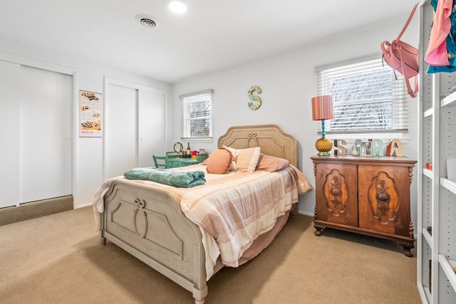 bedroom featuring carpet flooring, visible vents, and multiple closets