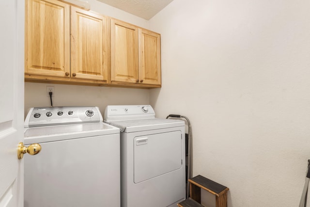 laundry area with cabinet space, a textured ceiling, and washing machine and clothes dryer