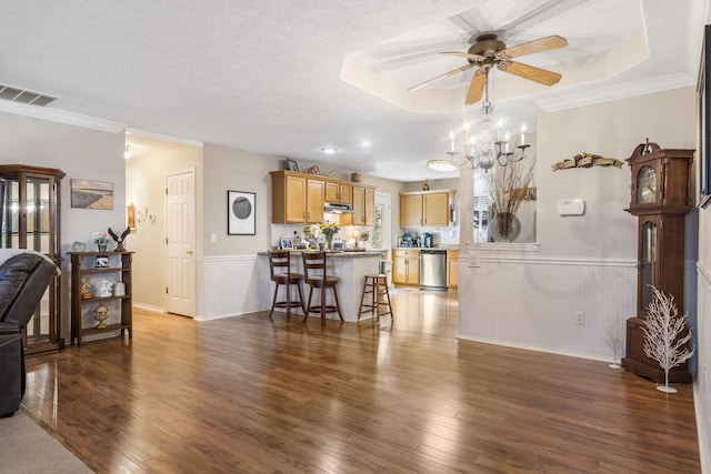 living area featuring ceiling fan with notable chandelier, a wainscoted wall, wood finished floors, and visible vents