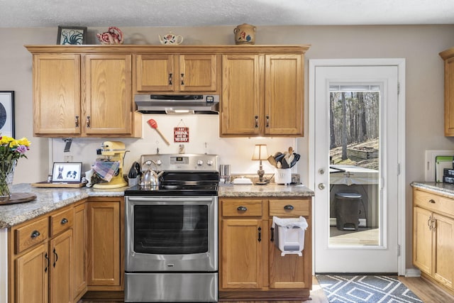 kitchen with electric stove, under cabinet range hood, light stone counters, a textured ceiling, and wood finished floors