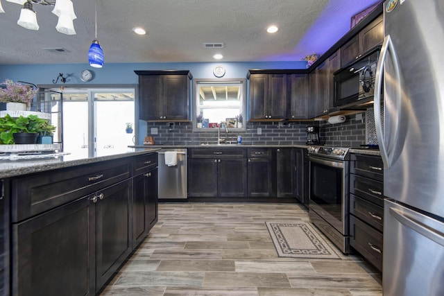 kitchen with tasteful backsplash, visible vents, light stone countertops, stainless steel appliances, and a sink