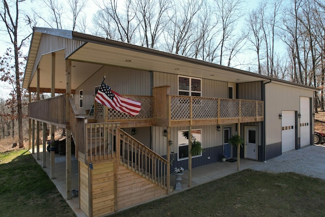 rear view of property with a lawn, a patio, a wooden deck, a garage, and stairs