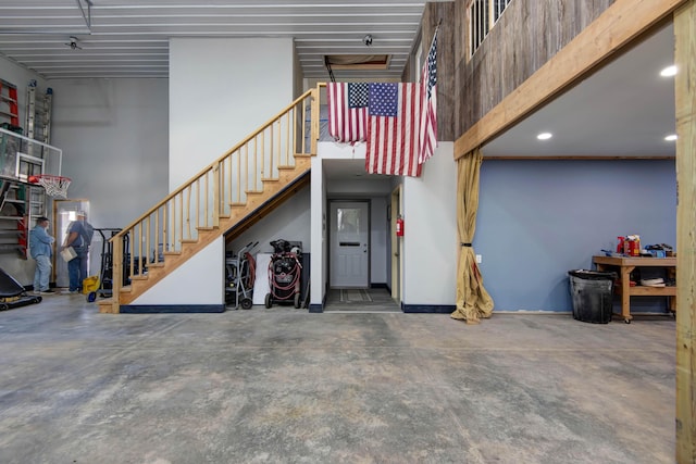 interior space with unfinished concrete floors, a high ceiling, and recessed lighting