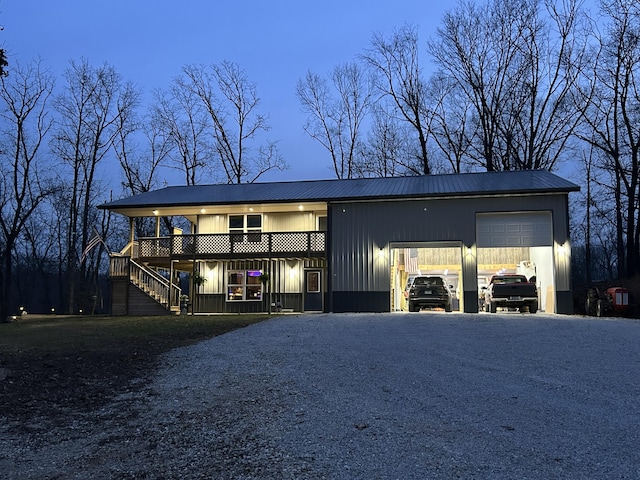 view of front of home with a garage, gravel driveway, and stairs