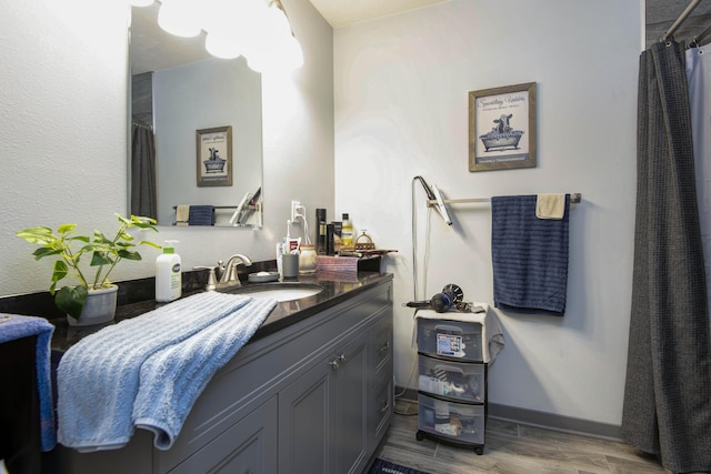 bathroom with vanity, a shower with shower curtain, baseboards, and wood finished floors