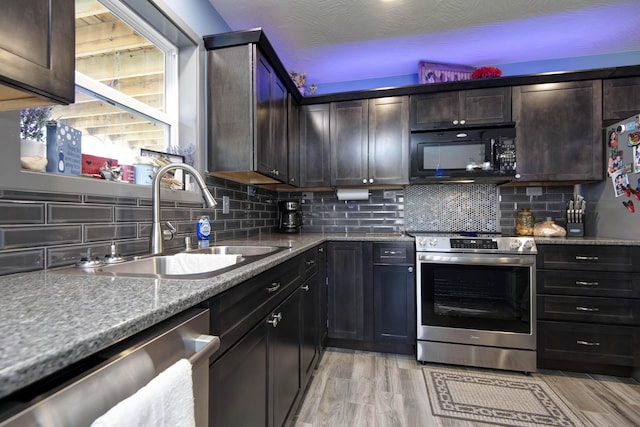 kitchen featuring decorative backsplash, light wood-style floors, appliances with stainless steel finishes, and a sink