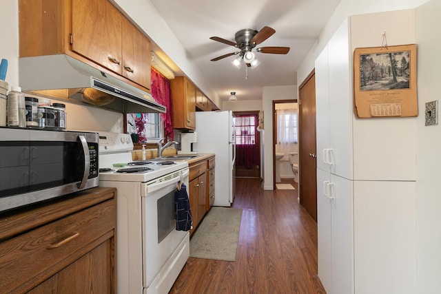 kitchen with a ceiling fan, white appliances, brown cabinetry, and under cabinet range hood