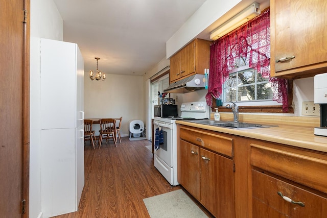 kitchen with under cabinet range hood, stainless steel microwave, white electric range, brown cabinets, and a chandelier