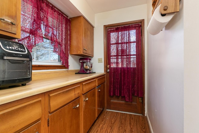 kitchen featuring brown cabinetry, plenty of natural light, dark wood-style flooring, and light countertops