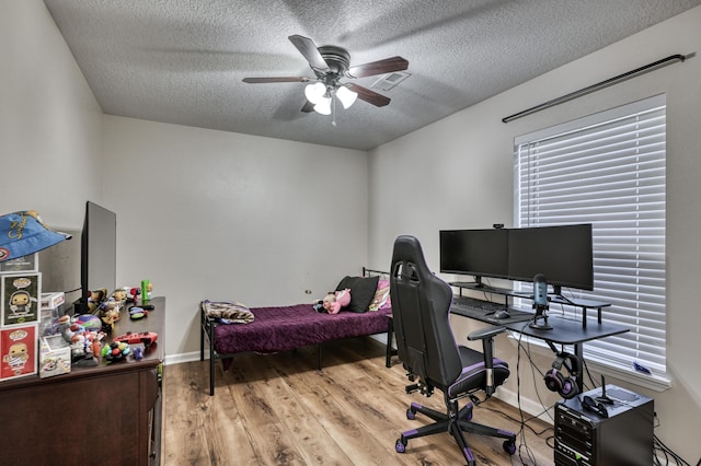 bedroom with visible vents, ceiling fan, baseboards, wood finished floors, and a textured ceiling