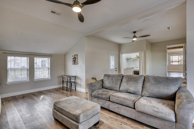 living room with wood finished floors, washing machine and dryer, visible vents, and ceiling fan