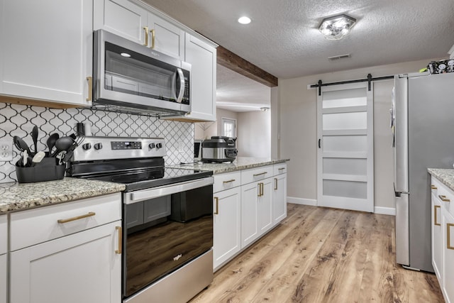 kitchen featuring visible vents, white cabinetry, stainless steel appliances, and light wood-style floors