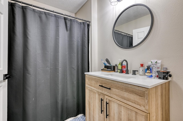 bathroom featuring a textured ceiling, vanity, and a textured wall