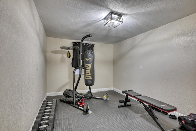 workout room with a textured wall, baseboards, and a textured ceiling