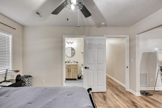 bedroom featuring a textured ceiling, baseboards, visible vents, and light wood-type flooring