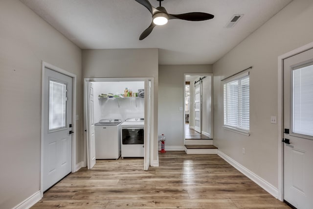 foyer entrance featuring washer and clothes dryer, visible vents, light wood-style flooring, and a ceiling fan