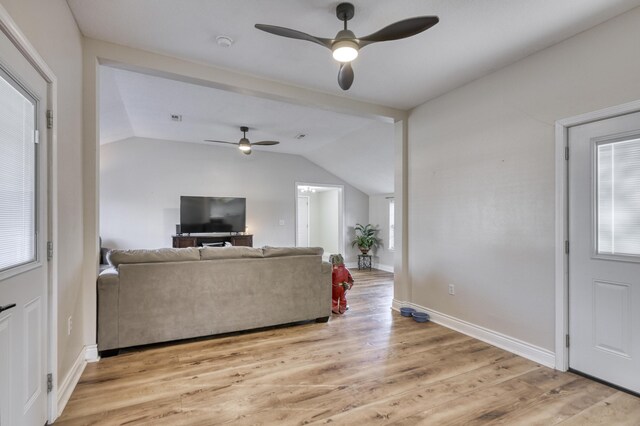 living area with a wealth of natural light, light wood-style floors, a ceiling fan, and vaulted ceiling