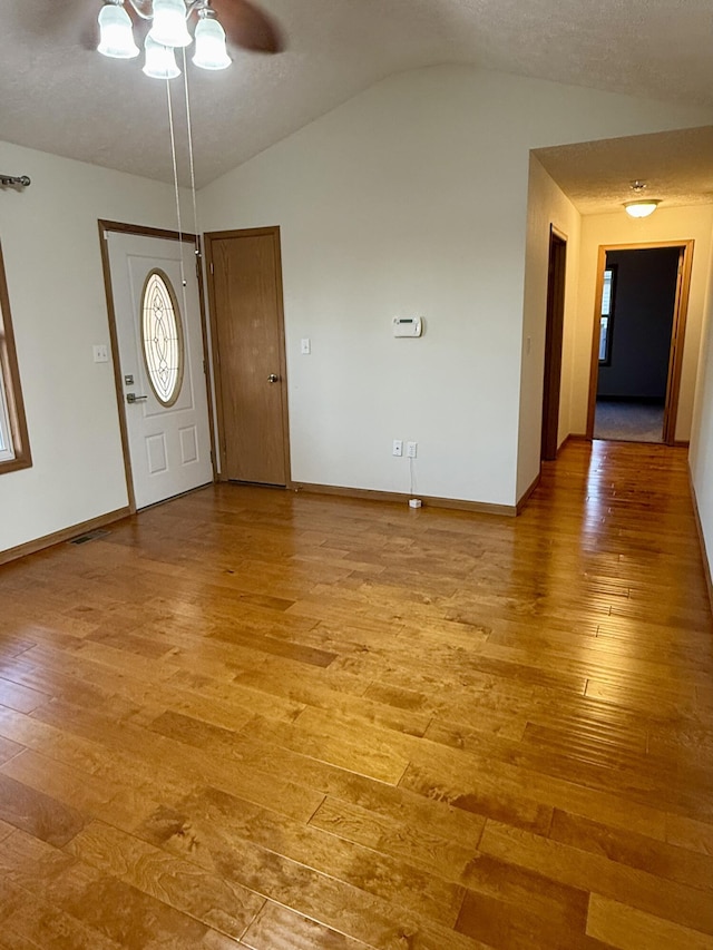 entrance foyer featuring lofted ceiling, light wood-style flooring, and baseboards