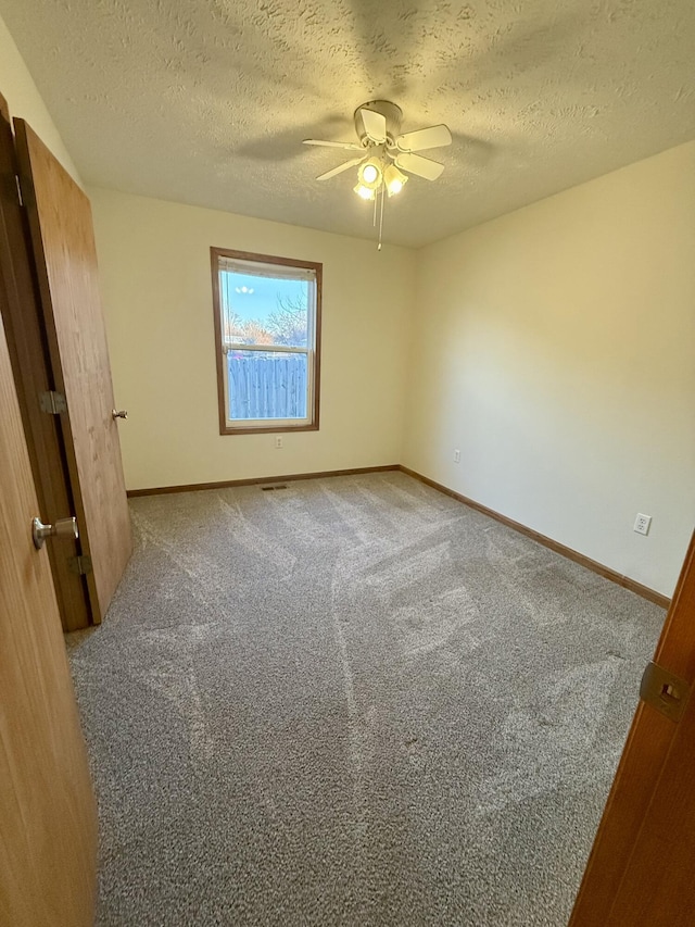 unfurnished bedroom featuring baseboards, carpet floors, a textured ceiling, and ceiling fan