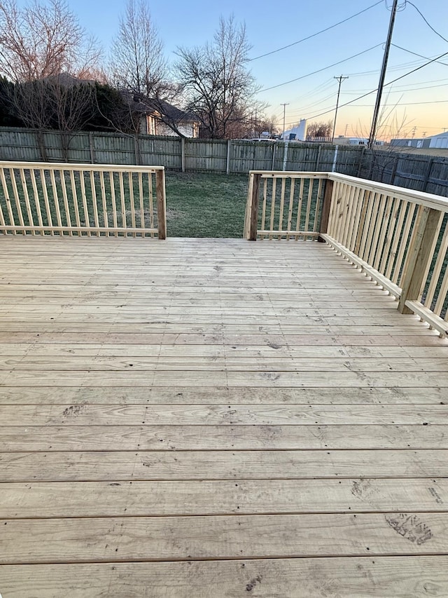 deck at dusk with a fenced backyard