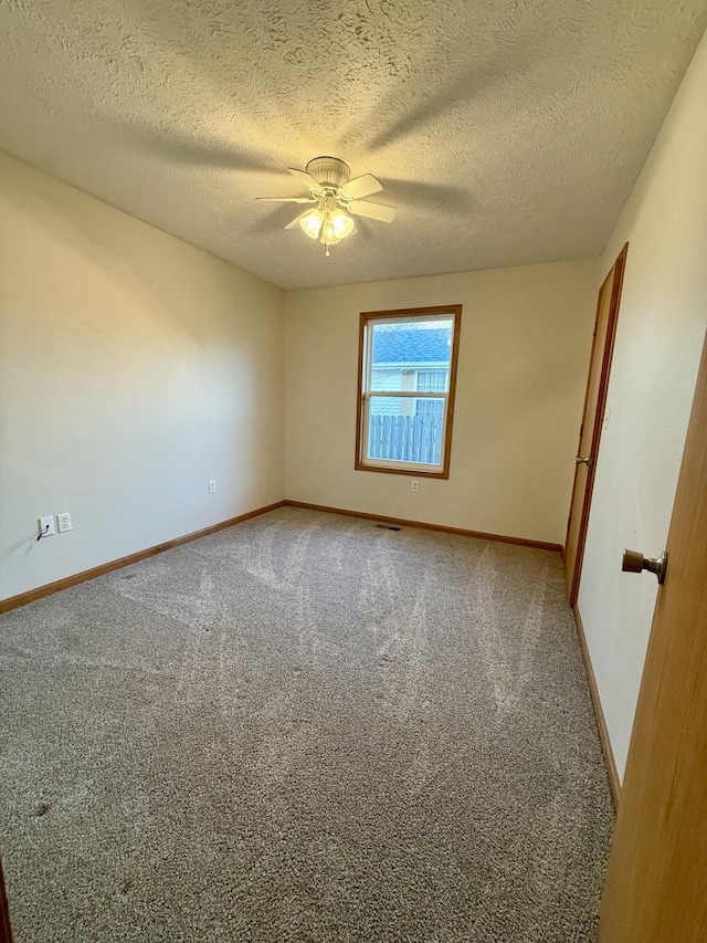 carpeted spare room featuring baseboards, a textured ceiling, and a ceiling fan