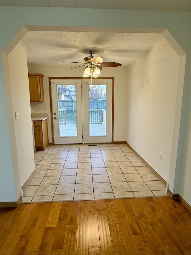 doorway to outside featuring baseboards, ceiling fan, a textured ceiling, and light wood-style floors