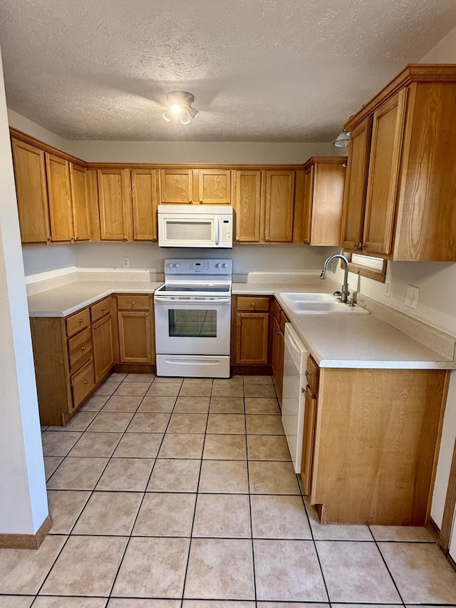 kitchen with a sink, white appliances, light tile patterned flooring, and light countertops