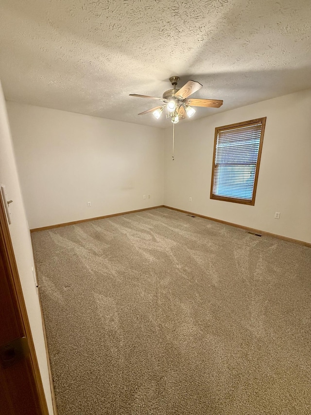 spare room featuring a textured ceiling, baseboards, carpet floors, and ceiling fan