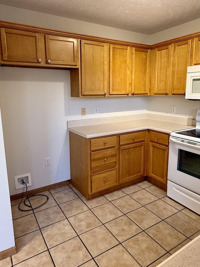 kitchen featuring white appliances, light tile patterned floors, brown cabinets, and a textured ceiling