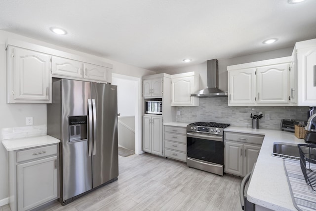 kitchen featuring tasteful backsplash, stainless steel appliances, wall chimney exhaust hood, and a sink