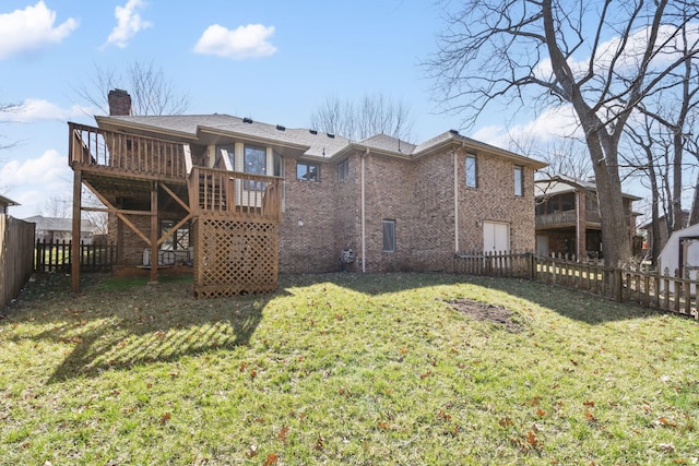 back of house featuring a wooden deck, a yard, a fenced backyard, a chimney, and brick siding