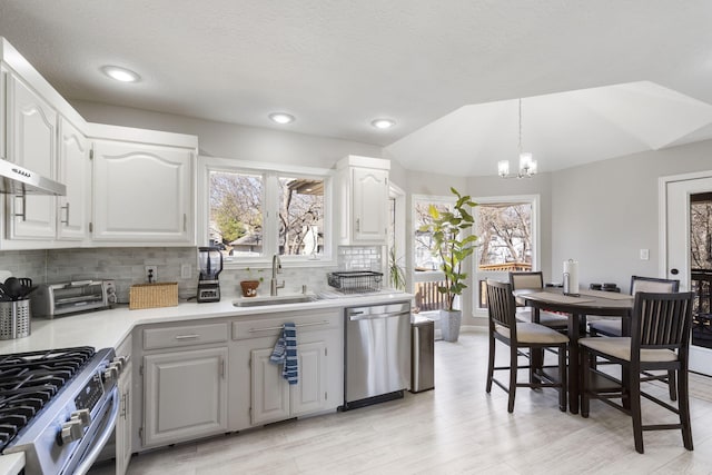 kitchen featuring tasteful backsplash, a chandelier, light countertops, appliances with stainless steel finishes, and a sink