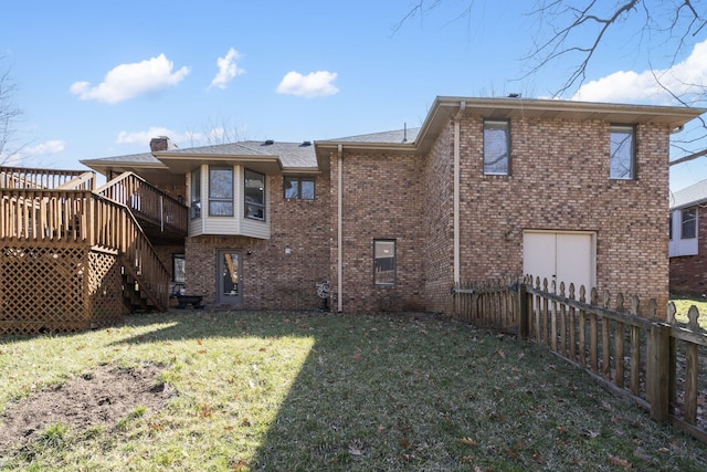 rear view of property featuring a lawn, fence, a wooden deck, brick siding, and a chimney