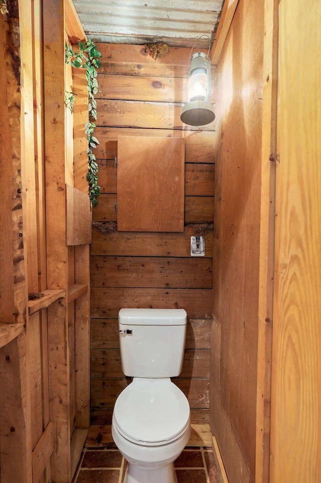 bathroom with toilet and wood walls