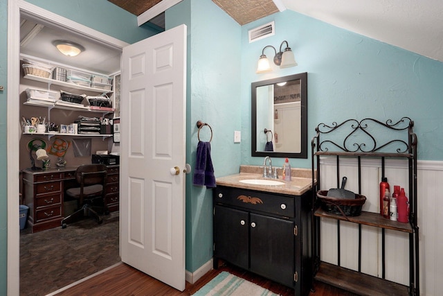 bathroom with a spacious closet, visible vents, wainscoting, wood finished floors, and vanity