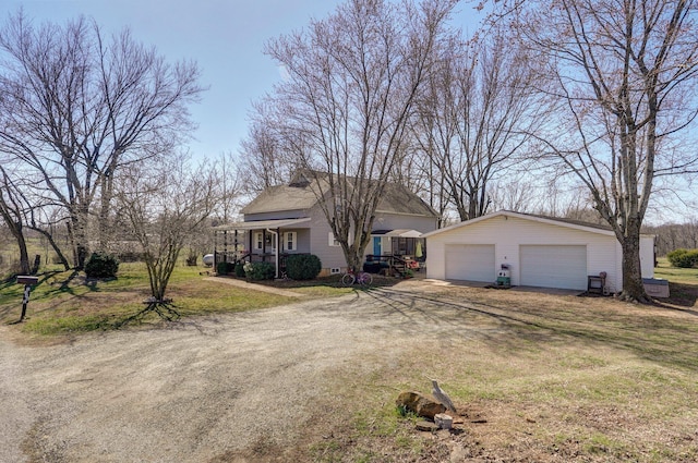 view of front facade with an outbuilding, a front yard, driveway, covered porch, and a garage