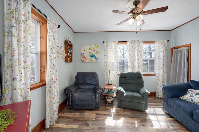 living area with wood finished floors, a ceiling fan, and ornamental molding