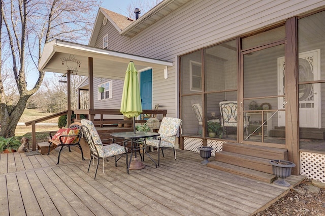 wooden terrace with outdoor dining area and a sunroom