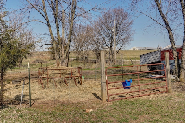 view of yard featuring an outbuilding, a rural view, and fence