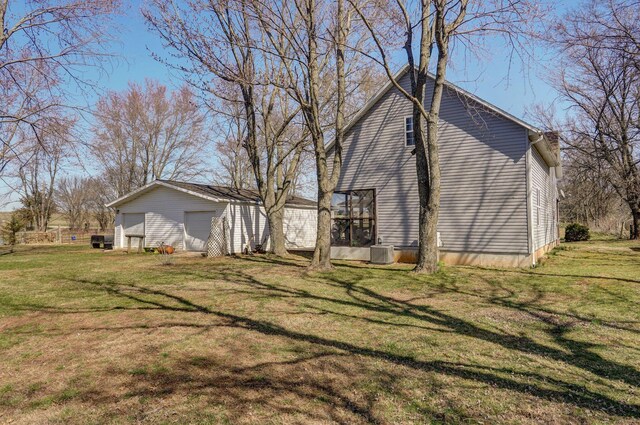 view of side of property with a garage, a lawn, central AC unit, and an outdoor structure