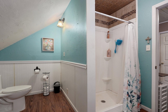 full bathroom with a wainscoted wall, toilet, wood finished floors, and a shower stall