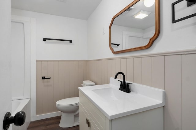 bathroom featuring vanity, wood finished floors, visible vents, a wainscoted wall, and toilet