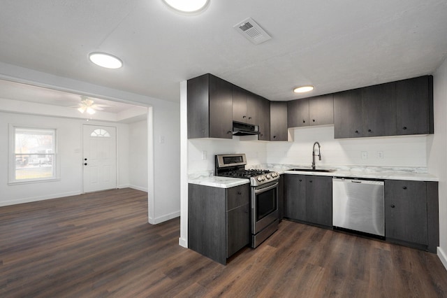 kitchen featuring range hood, visible vents, dark wood finished floors, a sink, and stainless steel appliances