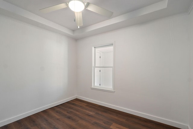 unfurnished room featuring a tray ceiling, baseboards, ceiling fan, and dark wood-style flooring