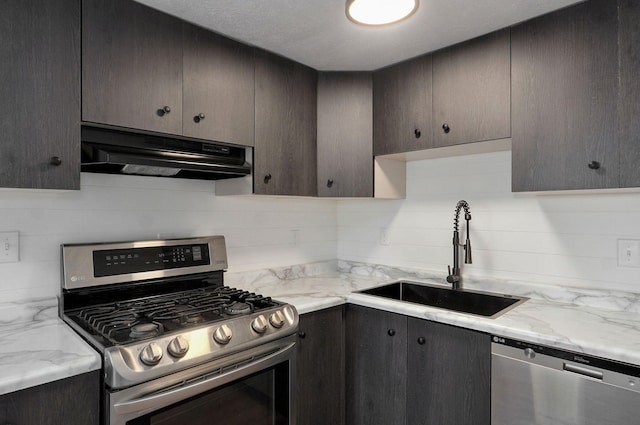 kitchen with under cabinet range hood, decorative backsplash, appliances with stainless steel finishes, and a sink